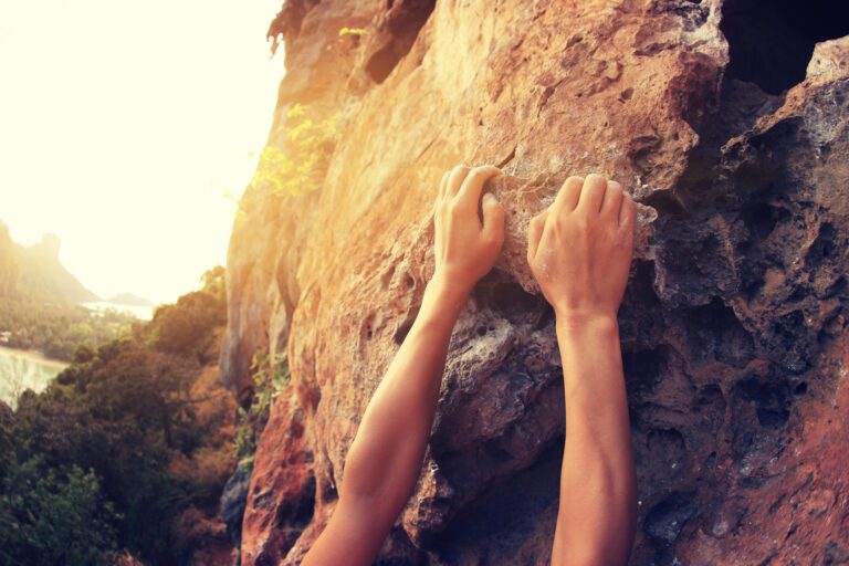 Person’s Hands Gripping a Rocky Surface
